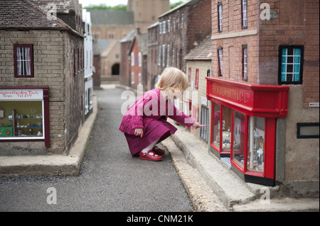 A little girl wanders around the streets of Wimborne Model Village in Wimborne, Dorset Stock Photo