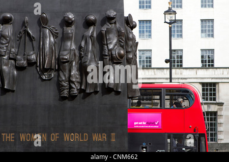 A London Bus passes the women of world war II memorial in Whitehall. Stock Photo
