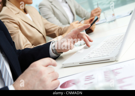 Businessman using laptop, his two colleagues working on background Stock Photo