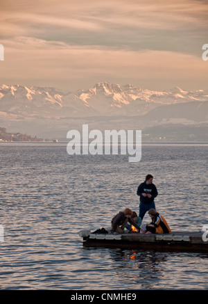 Young boys around a bonfire in the middle of lake Zurich Stock Photo