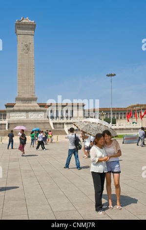 Chinese tourists in Tiananmen Square taking photographs of each other with The Monument to the People's Heroes and The Great Hal Stock Photo