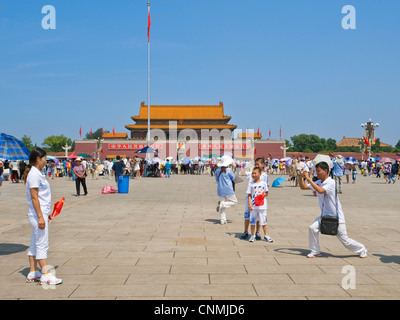 Chinese tourists in Tiananmen Square taking photographs of each other with the entrance to The Forbidden City in the background. Stock Photo