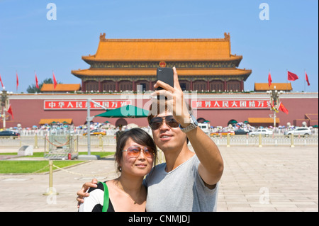 A young Chinese couple take a picture of themselves with a mobile phone in Tiananmen Square. Stock Photo