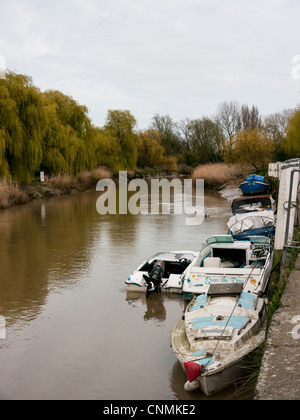 Boats moored on the river estuary at Sandwich, Kent, UK with tree reflections Stock Photo