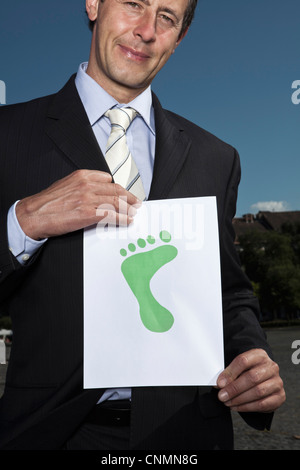Businessman holding footprint on paper Stock Photo