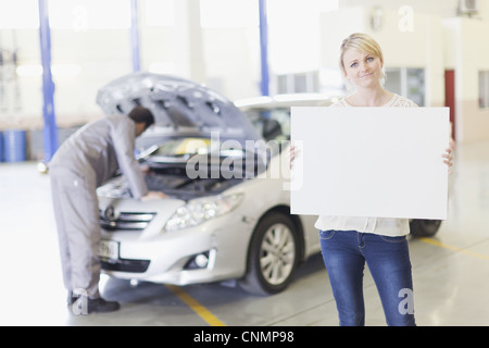Woman holding blank card in garage Stock Photo