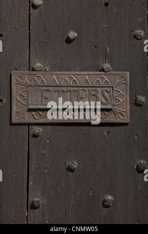 Close up of ornate old letter box letterbox on a wooden door England UK United Kingdom GB Great Britain Stock Photo