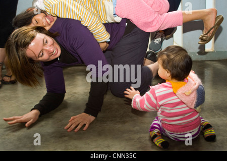 Horizontal view of Vietnamese children having fun playing with Western tourist at an orphanage near Hue. Stock Photo