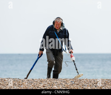 Man using a metal detector on a beach in the Uk. Stock Photo