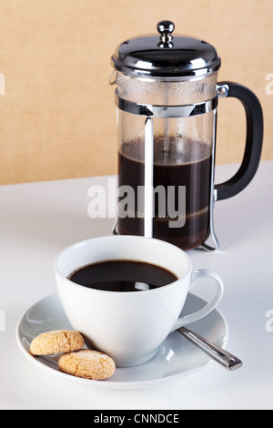 Photo of a cup of coffee with Amaretti biscuits on the saucer and a cafetiere full of freshly brewed coffee.