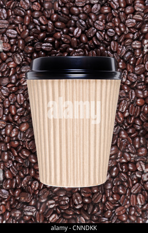 Photo of a disposable paper coffee cup with a mixture of arabica and robusta beans in the background. Stock Photo