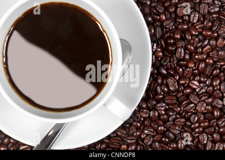 Overhead photo of a cup of coffee sitting on fresh roasted arabica and robusta coffee beans. Stock Photo
