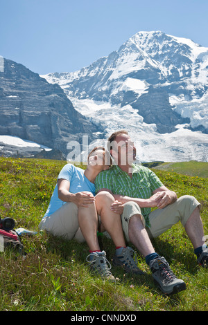 Couple Sitting on Mountain Side, Bernese Oberland, Switzerland Stock Photo