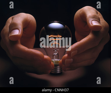 Hands cupping glowing light bulb Stock Photo