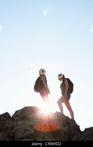 Silhouette of hikers standing on rock Stock Photo