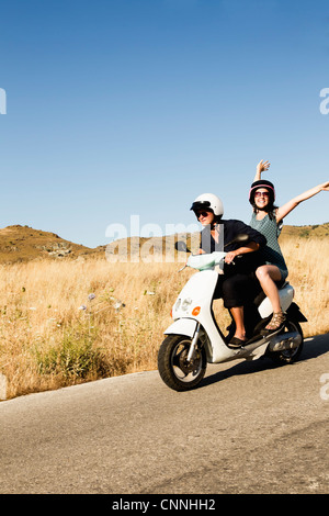 Women driving scooter on rural road Stock Photo