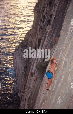 A rock climber climbing the sheer seacliffs in Gozo in Malta. Stock Photo