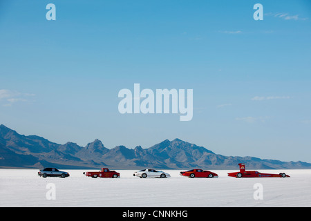 line up of vehicles across Bonneville Salt Flats next to the horizon and mountains with blue summer sky Stock Photo
