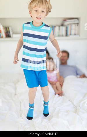 Boy jumping on parents’ bed Stock Photo