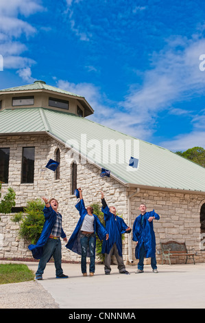 Group of highschool students celebrating their graduation by jumping and throwing caps Stock Photo