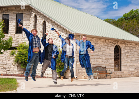 Group of highschool students celebrating their graduation by jumping and throwing caps Stock Photo