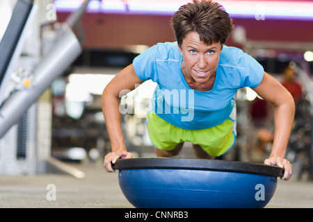 Woman doing Push-ups with Balance Ball in Gym Stock Photo