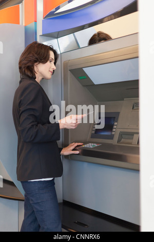 Businesswoman using ATM outdoors Stock Photo