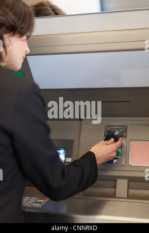 Businesswoman using ATM outdoors Stock Photo