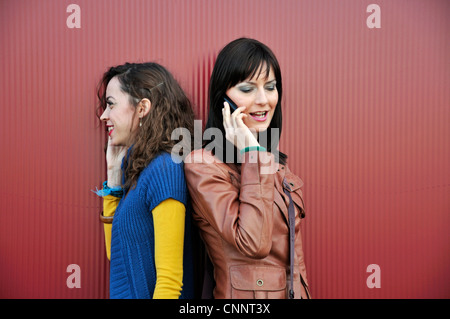 Two young women outdoors talking on cell phone Stock Photo