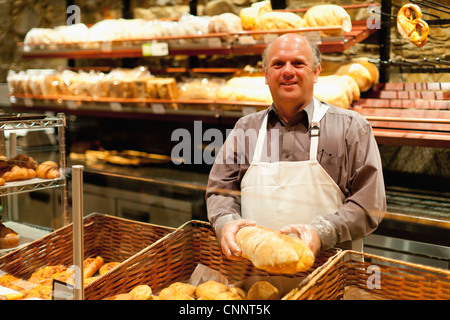 Smiling baker holding loaf of bread Stock Photo