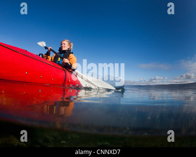 Woman kayaking in still lake Stock Photo