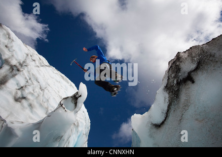 Hiker jumping in between glaciers Stock Photo