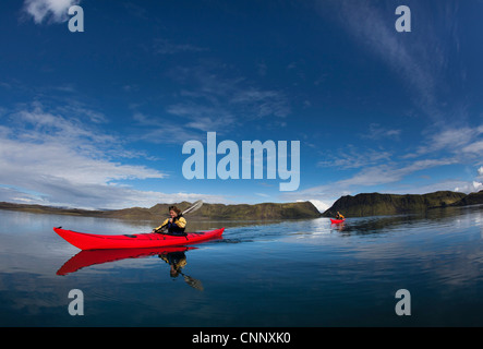 Man rowing canoe in still lake Stock Photo