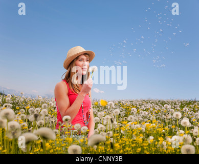 Woman blowing dandelions outdoors Stock Photo
