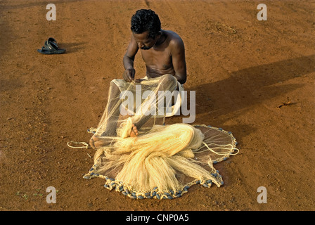 Fisherman mending nets on beach, Trivandrum, Kerala, India Stock Photo
