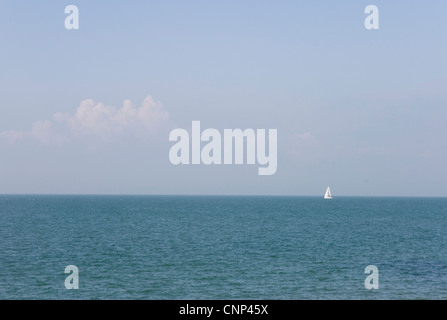 Blue/green sea - blue sky - a white cloud - a single white sail on the horizon Stock Photo