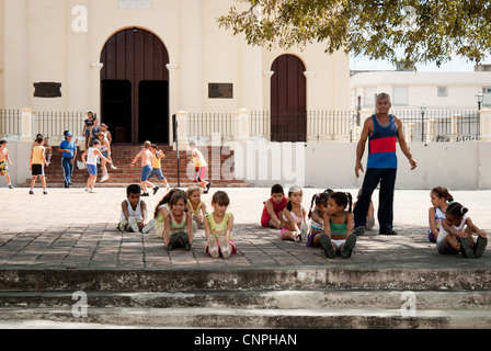 Cuban girls during their PE lesson outside a church in Santa Clara. Boys ale playing football in the background Stock Photo