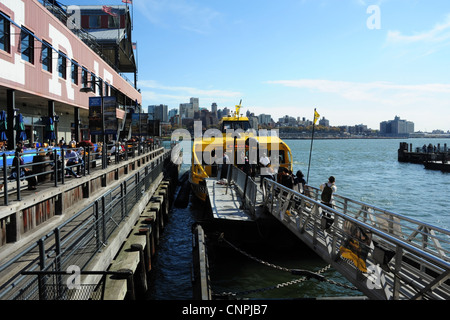 Blue sky view, towards Brooklyn skyline, yellow water taxi moored East River alongside Pier 17, South Street Seaport, New York Stock Photo