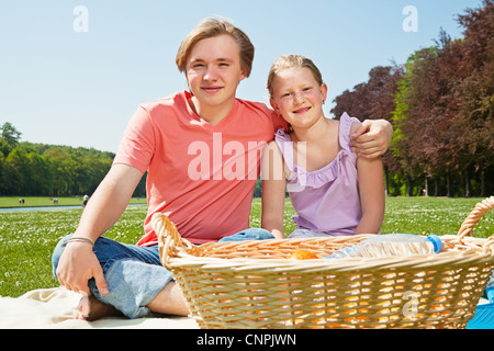 Teenager brother and sister enjoying a picnic in the park in a bright ...