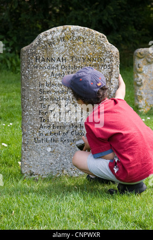 Young boy examining the grave of Hannah Twynnoy in the churchyard of Malmesbury Abbey Stock Photo
