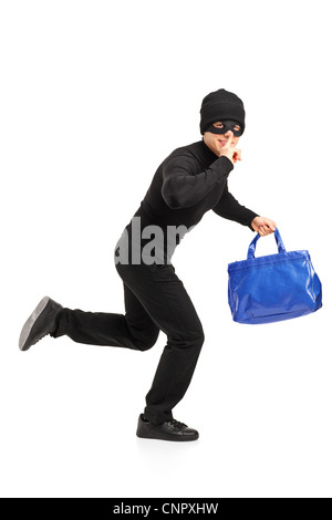 Full length portrait of a thief running with a stolen purse and finger on lips gesturing silence isolated on white background Stock Photo