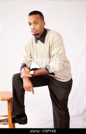 Handsome young black man with pensive expression resting and leaning on his knee Stock Photo