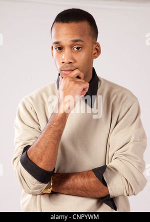 Handsome young black man with pensive expression and hands on his chin, looking pensive and thoughtful Stock Photo