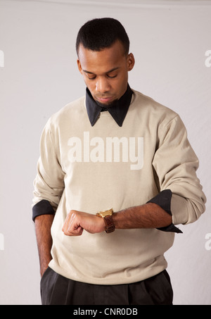 Thoughtful young black man, wearing sweater and looking all pensive looking at his watch Stock Photo