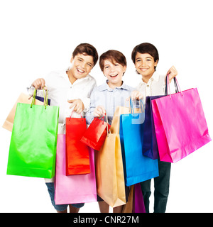 Happy boys with gifts, kids carrying colorful shopping bags with Christmas presents isolated over white background, holidays Stock Photo