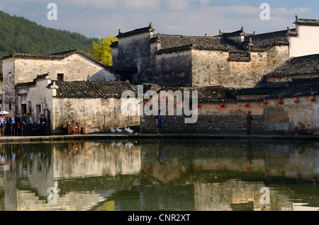Ancient buildings with geese and tourists reflected in the still Half moon pond in Hongcun village Peoples Republic of China Stock Photo