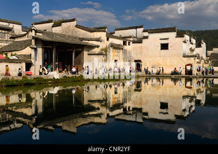 Ancient white buildings and tourists reflected in the still Half moon pond in Hongcun village Peoples Republic of China Stock Photo