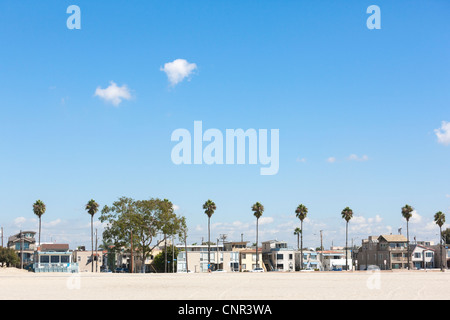 Long Beach California, East E Ocean Boulevard beach front homes. Looking out over the beachfront sand, with palm trees. Stock Photo