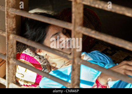 country life in India, young lady relaxes at an open window taking in the sun beams Stock Photo