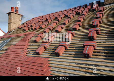 Red concrete roof tiles placed on a domestic property roof as part of a renovation project Stock Photo